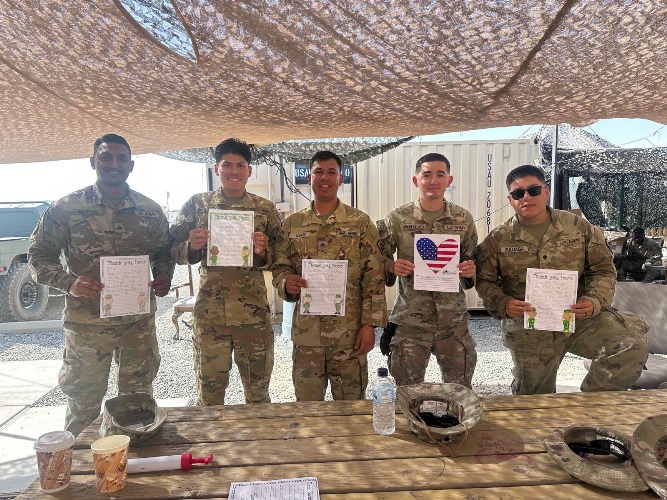 Deployed service members holding care packages from Forgotten Soldiers Outreach WE CARE Program